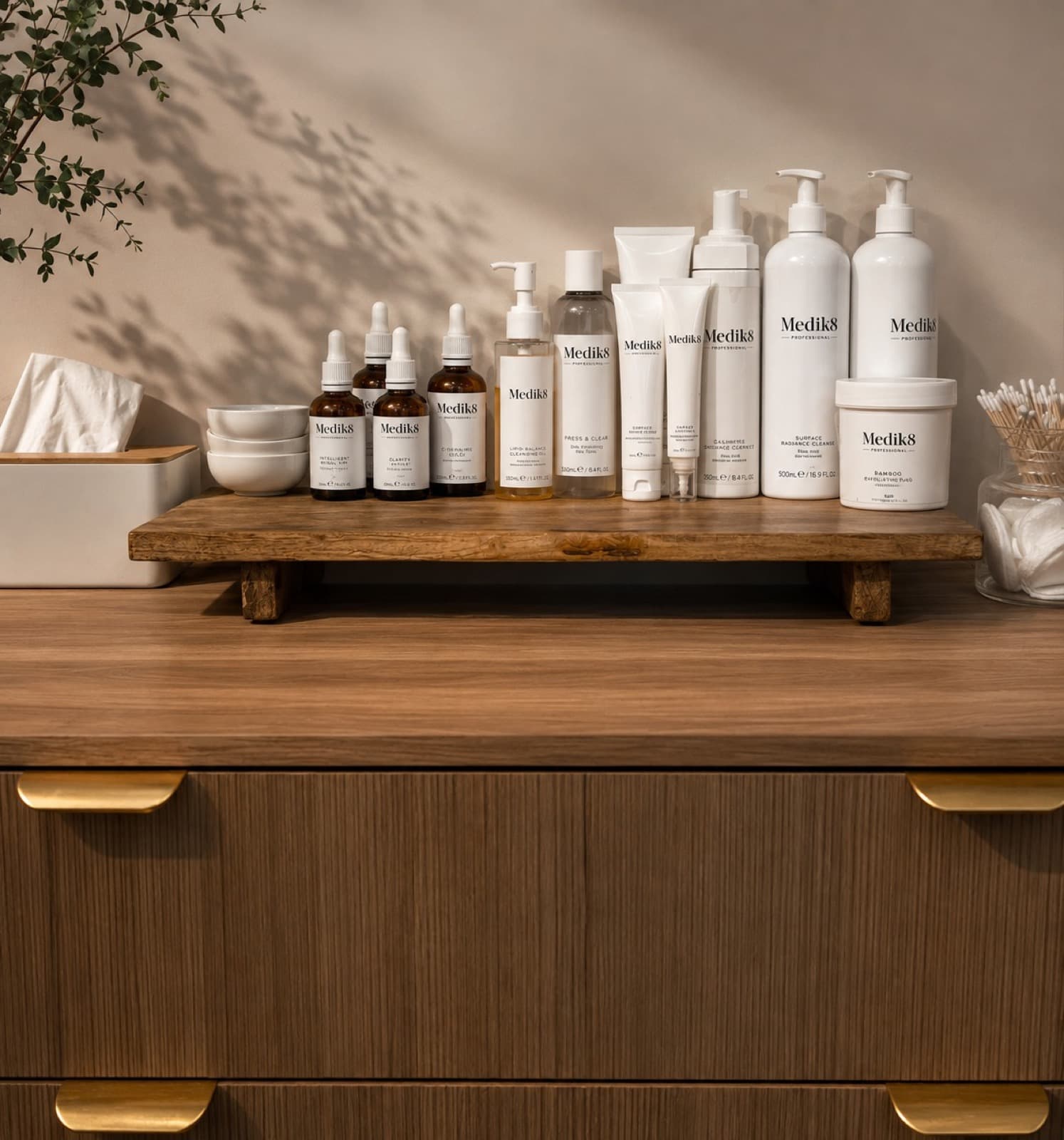 The shelf above the counter, tissues, small bowls and cotton buds beside a row of bottles.